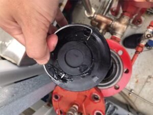 Engineer in process of removing used lubricant filter element from industrial machinery